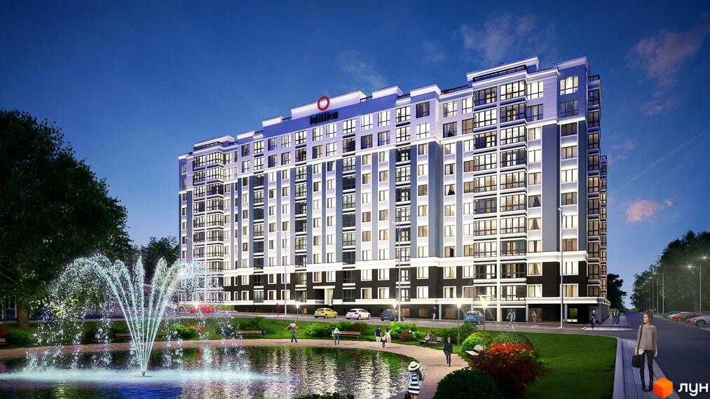 Житловий комплекс Idilika ввечері, багатоповерховий будинок з підсвіченими вікнами та балконами. Поруч з будинком розташований ставок з фонтаном, зелені насадження та прогулянкові доріжки.