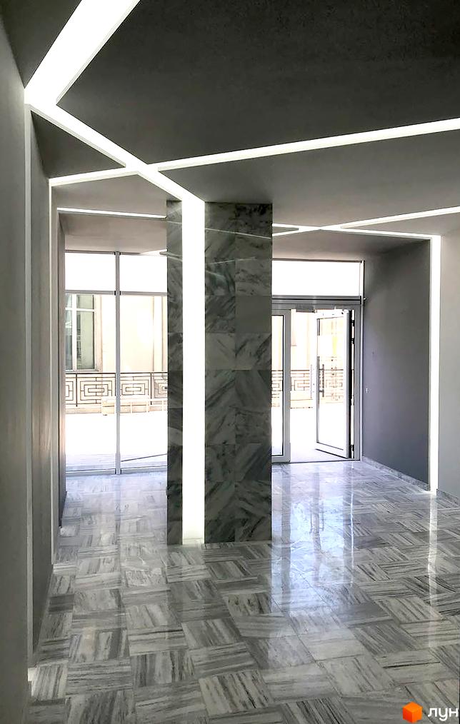 Інтер'єр холу в ЖК Миконос: мармурова підлога, колони з мармуру, світлодіодне освітлення. Просторий коридор з виходом на вулицю.