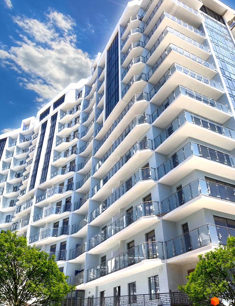 Висотна будівля ЖК Mykonos з балконами та скляними огорожами. На передньому плані зелені дерева, блакитне небо з хмарами.