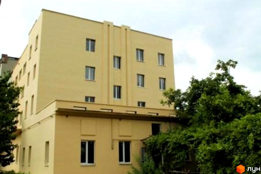 Житловий комплекс Бериславське шосе, 2б: світло-жовта багатоповерхова будівля з прямокутними вікнами. Будівля оточена густою зеленою рослинністю.