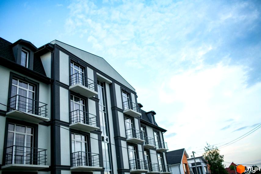 Багатоквартирний будинок Клубний будинок Giverny HOUSE зі світлим фасадом, темними елементами та балконами. На задньому плані видно небо та інші будівлі.