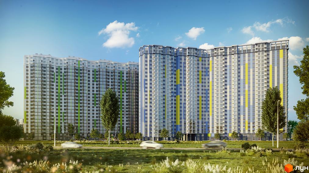 Високоповерховий житловий комплекс з різнокольоровими фасадами на тлі блакитного неба. На передньому плані зелена трава та дерева.