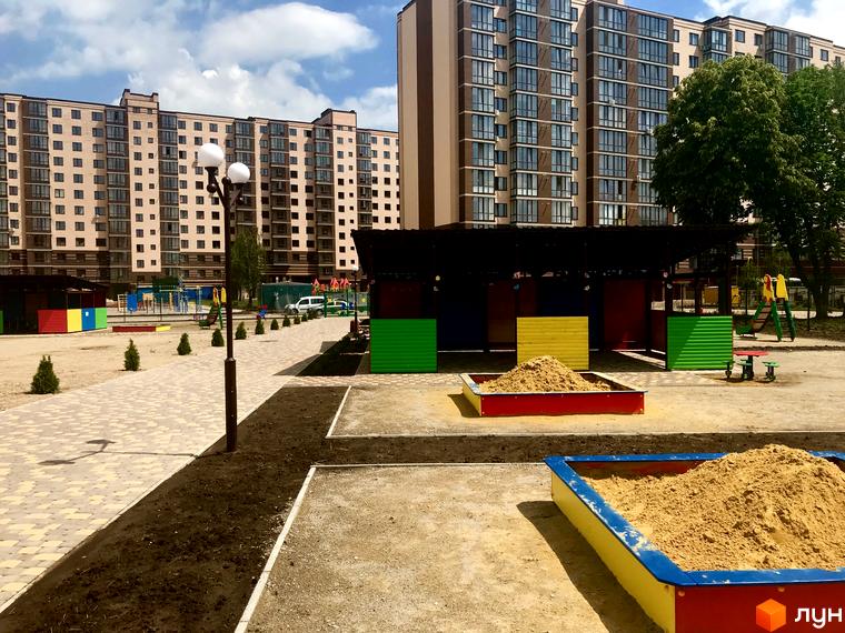 Житловий комплекс Андорра. Зовнішній вигляд багатоповерхових будинків та дитячого майданчика з пісочницями та гіркою.