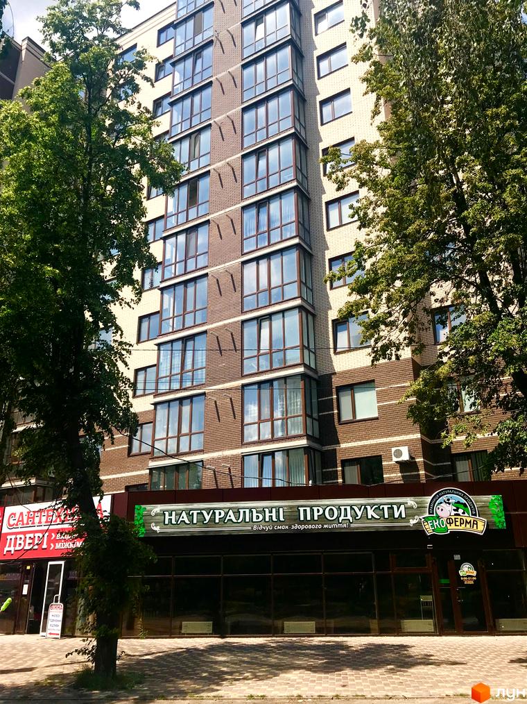 Житловий комплекс Андорра - сучасна новобудова з цегляним фасадом та великими вікнами. На першому поверсі розташовані магазини з вивісками