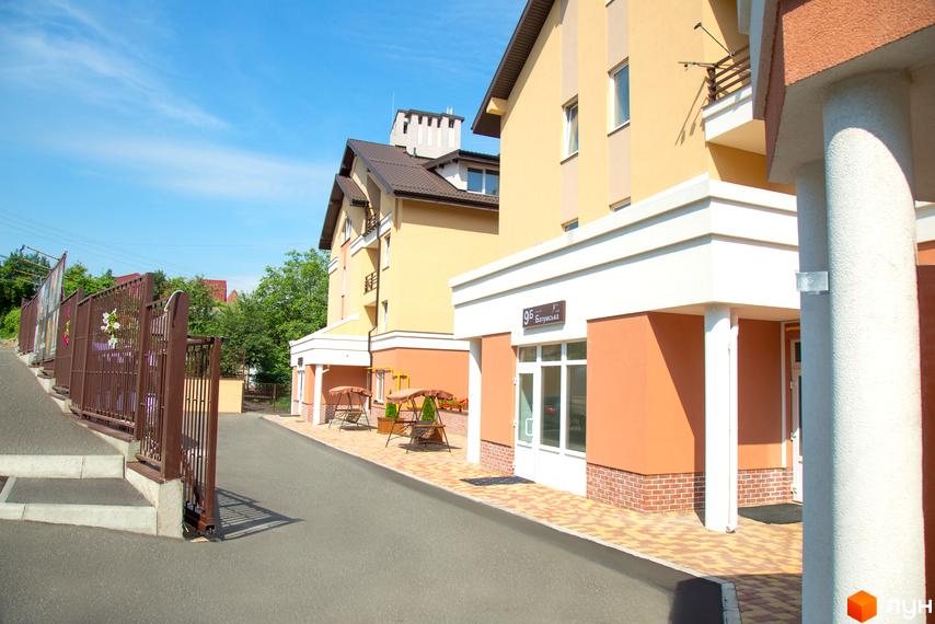 Житловий комплекс Comfort Club. Зовнішній вигляд жовто-помаранчевих будинків з білими навісами та коричневою огорожею. Прибудинкова територія з доріжками та гойдалками.