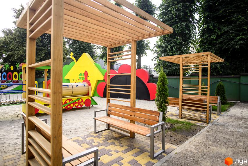 Дитячий майданчик у ЖК Відрадний з дерев'яними навісами та лавками. На території розташована ігрова зона у вигляді потяга та гірки.
