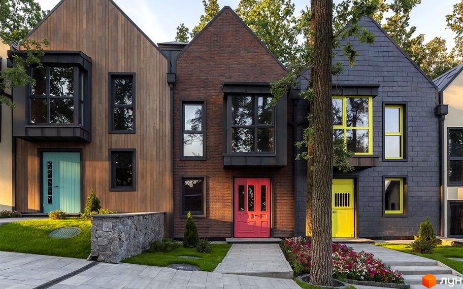 Зображення фасаду будинку в Котеджному містечку Oak Grove Town з яскравими дверима та вікнами. На прибудинковій території є доріжка, газон і квіти.