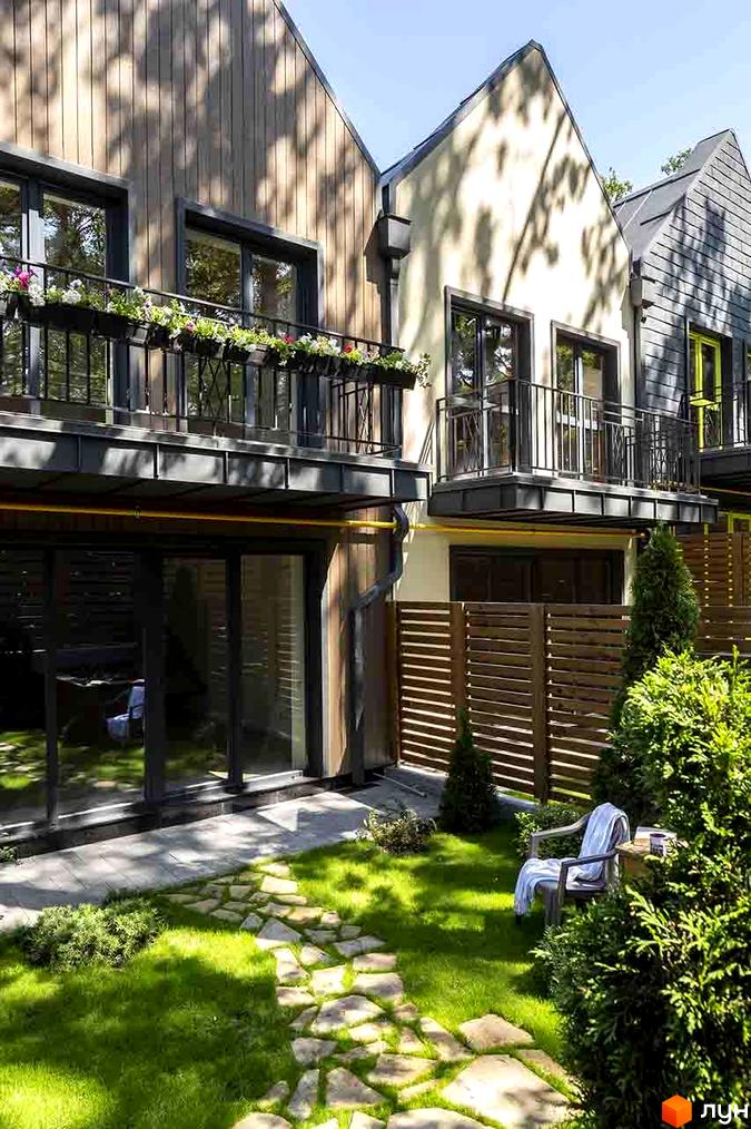 Котеджне містечко Oak Grove Town: фасади будинків з балконами, зелений газон, кам'яна доріжка та дерев'яна огорожа.