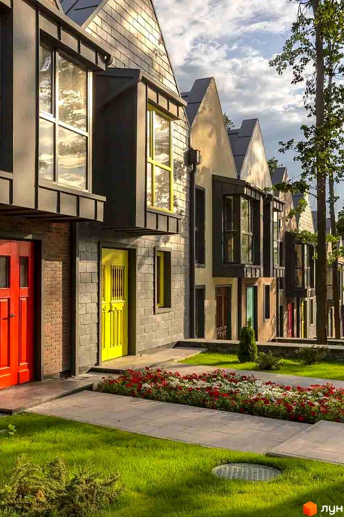 Зображення житлового комплексу КМ Oak Grove Town. Мальовничі будинки з яскравими дверима та доглянутою прибудинковою територією з квітами та газоном.