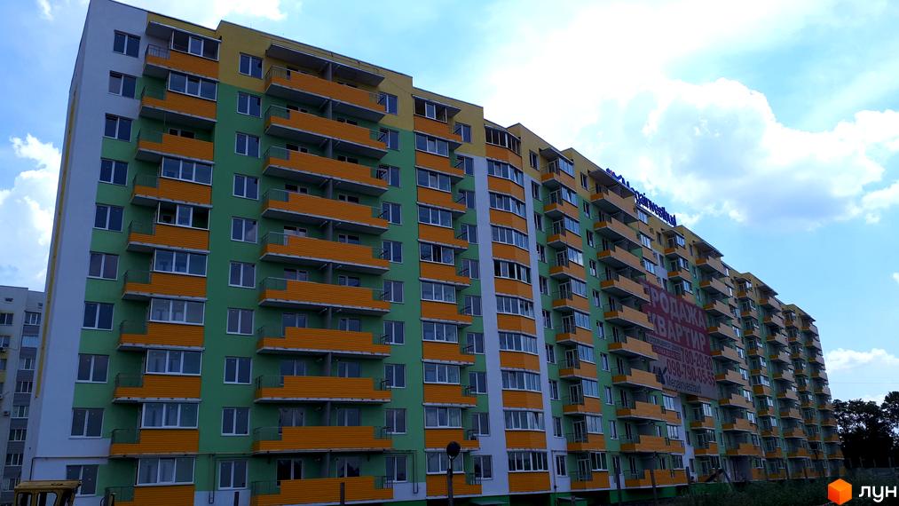 Зображення багатоповерхового будинку Житлового комплексу Райдужний з яскравими балконами. Фасад новобудови пофарбовано в зелений та жовтий кольори.