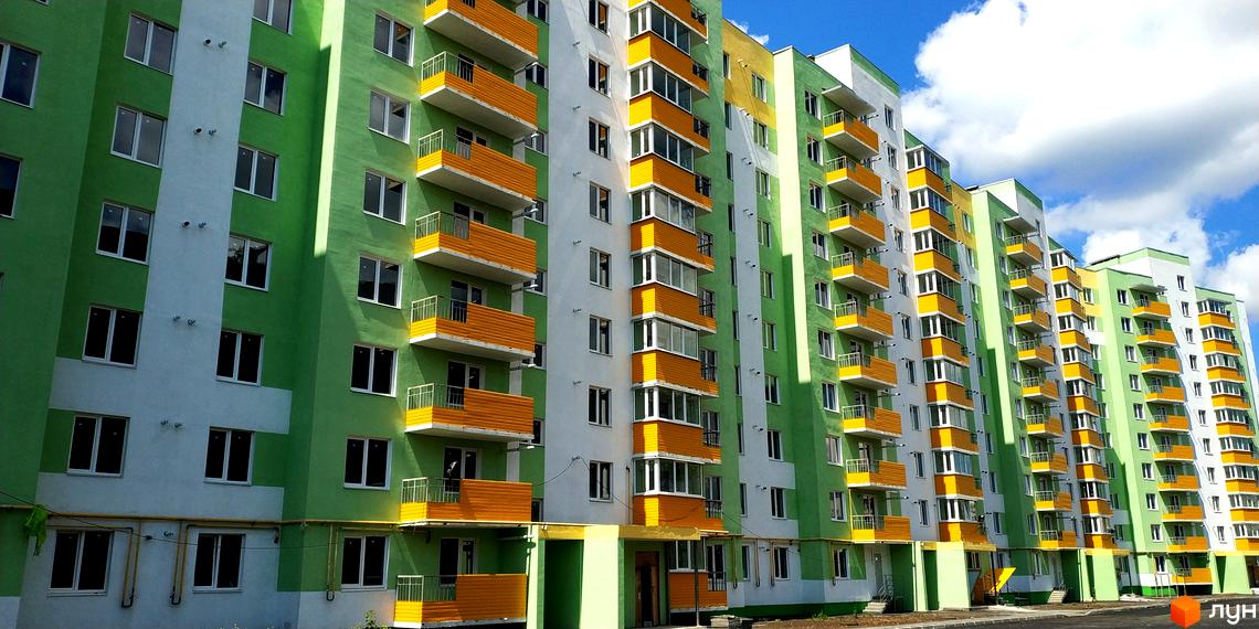 Фото фасаду багатоповерхового будинку в Житловому комплексі Райдужний. Яскраві кольори, балкони, вікна та прибудинкова територія.