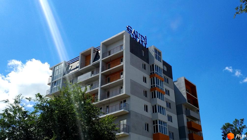 Сучасний житловий комплекс Gaudi Hall з яскравими фасадами та панорамними вікнами на тлі блакитного неба. Будинок має балкони та виступаючі елементи.