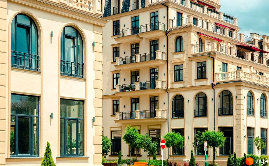 Зовнішній вигляд будинку Житлового кварталу Авторський: світлий фасад, аркові вікна, балкони. Прибудинкова територія з зеленими насадженнями.