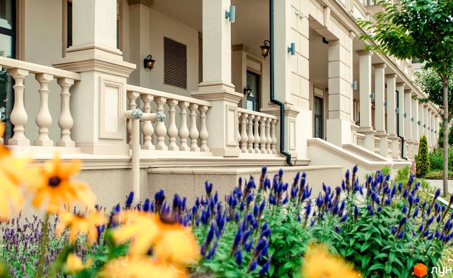 Фасад будинку в Житловому кварталі Авторський з колонами та балюстрадою. Перед будинком клумби з квітами.