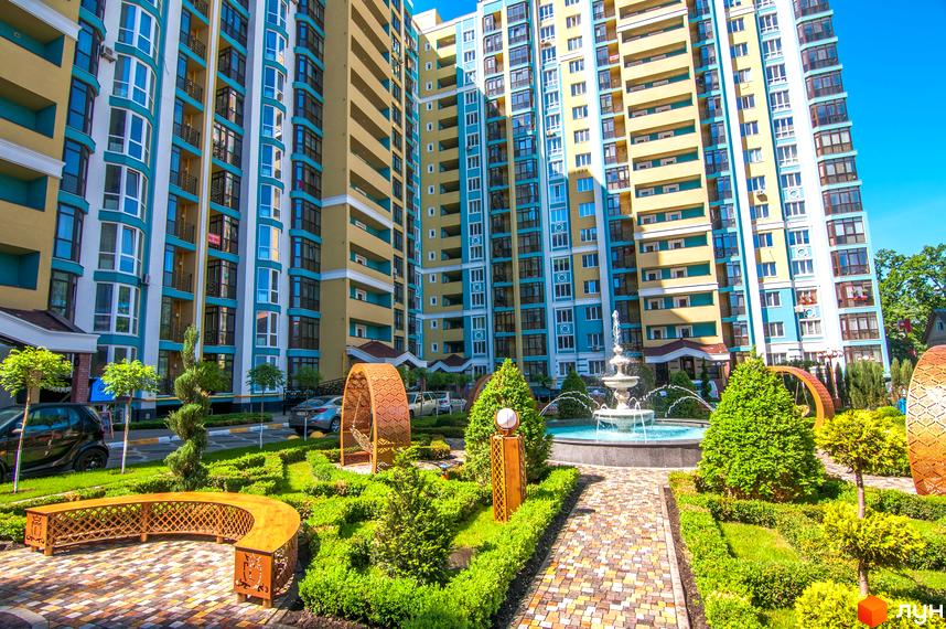 Житловий комплекс Версаль Парк з яскравими фасадами та доглянутою прибудинковою територією з фонтаном та зеленими зонами.