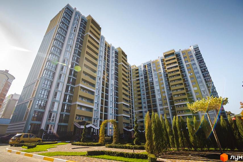 Житловий комплекс Версаль Парк - багатоповерхові будинки жовто-блакитного кольору з великою кількістю вікон. Доглянута прибудинкова територія з зеленими насадженнями та доріжками.