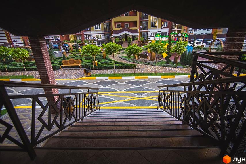 Зовнішній вигляд житлового комплексу Версаль Парк з доглянутою прибудинковою територією та дитячим майданчиком. Фото з сходів.