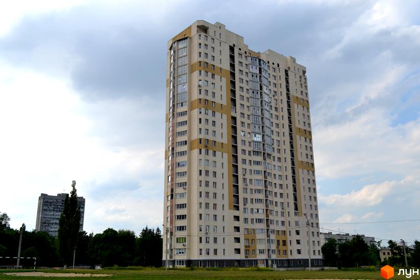 Житловий комплекс Ювілейний з висотною будівлею та прибудинковою територією, оточений зеленими насадженнями.