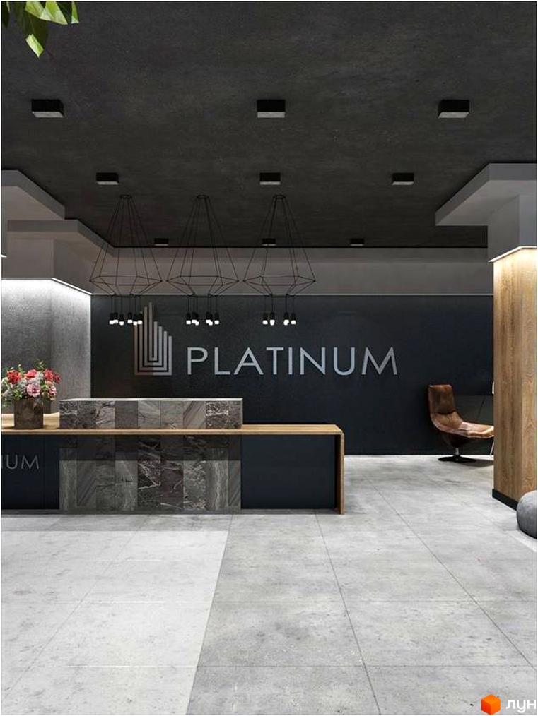 Інтер'єр вхідної групи Житлового комплексу Platinum Residence. Стійка ресепшн з оздобленням під камінь та логотип комплексу на стіні.
