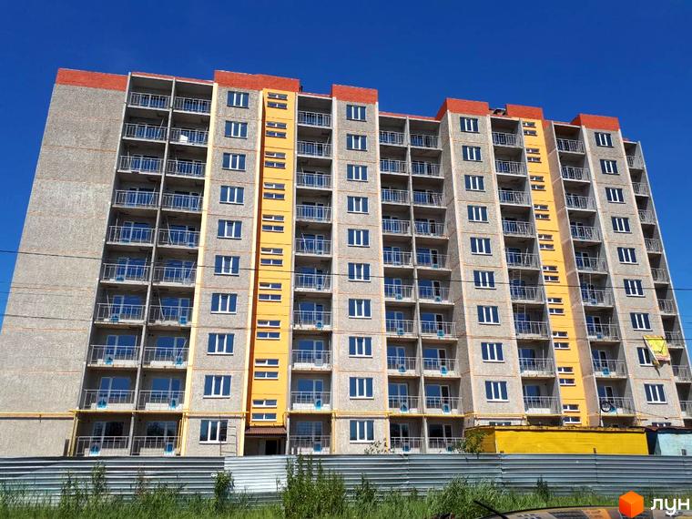 Зовнішній вигляд багатоповерхового будинку на вулиці Красносільського. Житловий комплекс з балконами та яскравими вставками на фасаді.