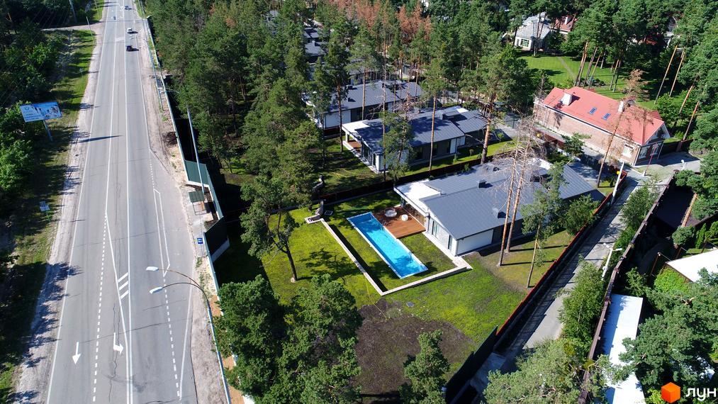 Котеджне містечко Хвойний квартал: будинки з темними дахами та світлими фасадами, оточені сосновим лісом. На території є басейн.