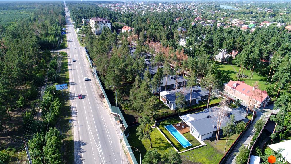 Вид на Котеджне містечко Хвойний квартал з висоти пташиного польоту. На передньому плані будинки з басейнами та доглянутою територією, поруч проходить дорога.