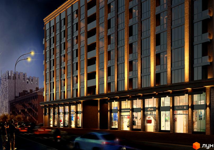 Нічний вигляд Житлового комплексу CRYSTAL RESIDENCE: багатоповерховий будинок з цегляним фасадом, освітленими вікнами та магазинами на першому поверсі.