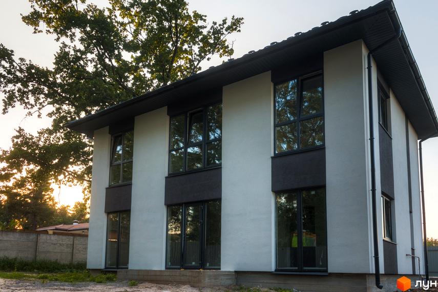 Зображення двоповерхового будинку в Котеджному містечку Lion`s Nest. Навколо будинку дерева та частково видно паркан.