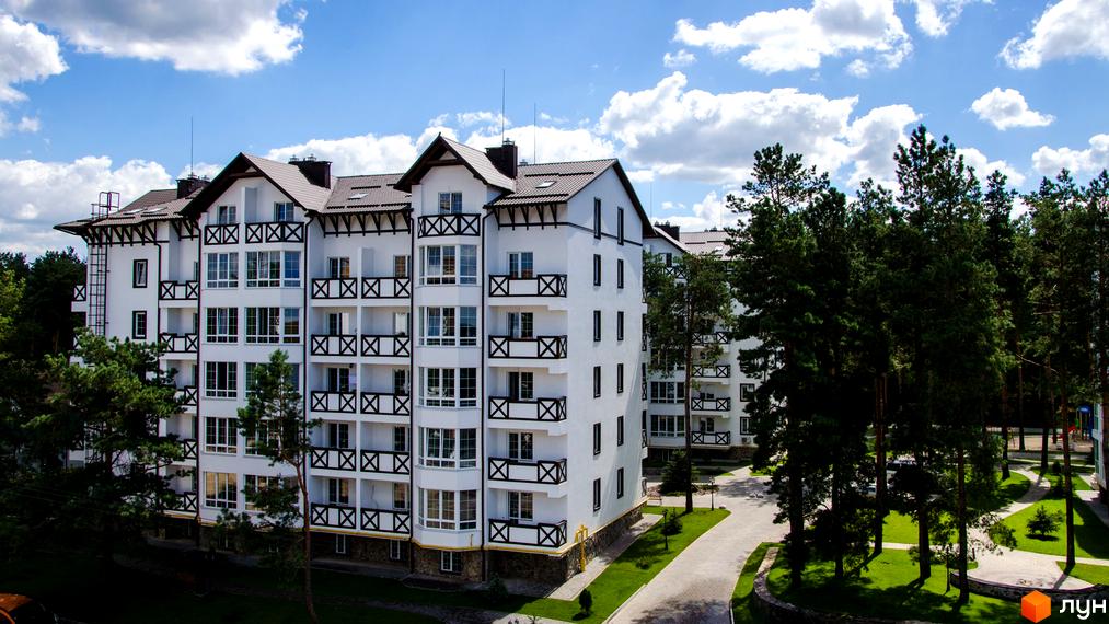 Житловий комплекс DESNA residence: білосніжні фасади з темними балконними огородженнями та коричневими дахами. Навколо комплексу – зелені насадження та доглянута територія.