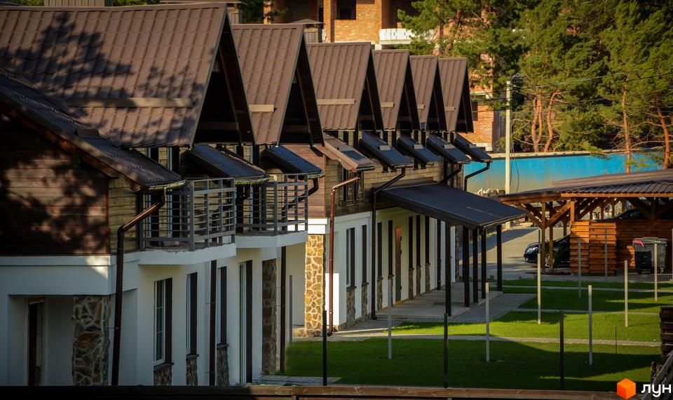 Таунхауси Desna Residence з коричневими дахами та білими фасадами. На території комплексу зелена галявина та навіси для автомобілів.