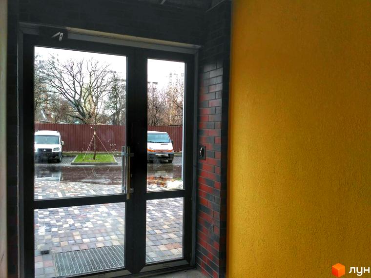 Клубний будинок Fort House. Вхідна група з подвійними скляними дверима та цегляною колоною. Прибудинкова територія з парковкою та деревами.