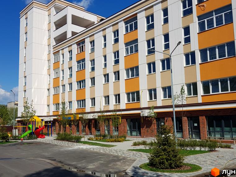 Зовнішній вигляд Клубного будинку Fort House. Багатоповерхова будівля з кольоровим фасадом та дитячим майданчиком на прибудинковій території.