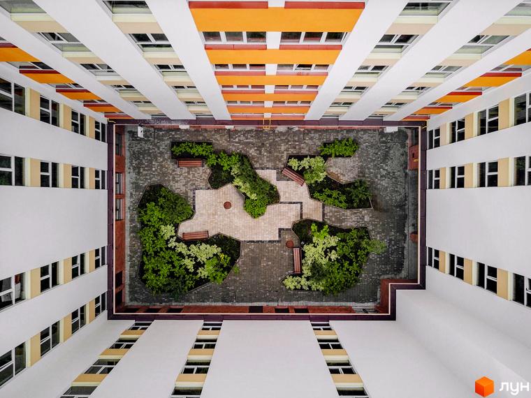 Клубний будинок Fort House з жовто-помаранчевими елементами фасаду та внутрішнім двориком з зеленими насадженнями та зонами відпочинку.