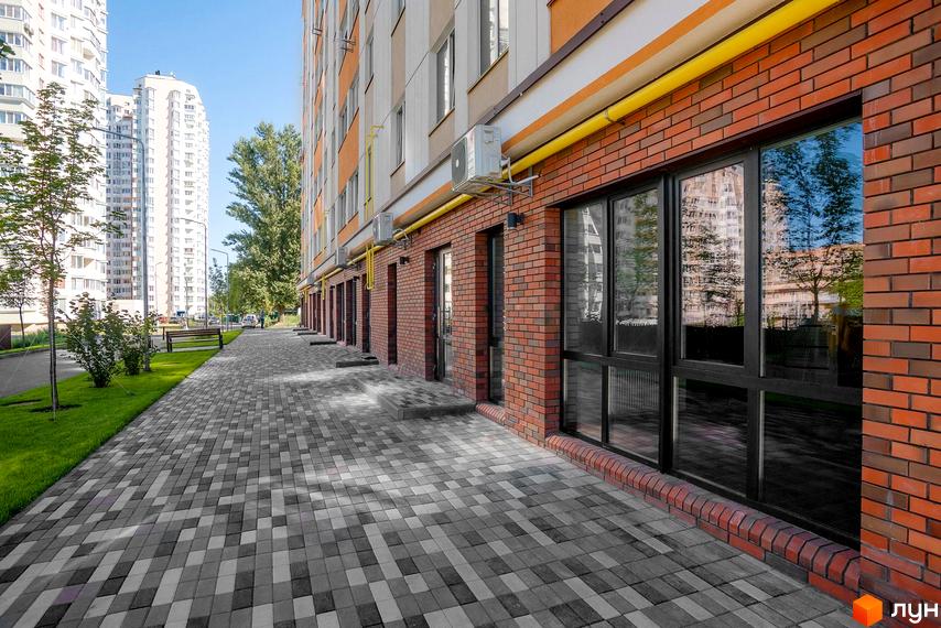 Клубний будинок Fort House з цегляним фасадом та великими вікнами. Поруч облаштована пішохідна доріжка та зелена зона з деревами.