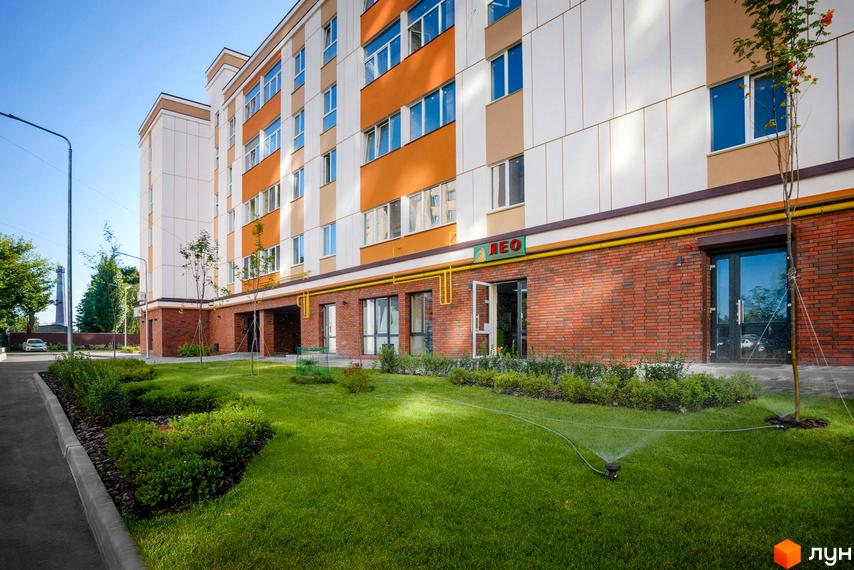 Зовнішній вигляд Клубного будинку Fort House. Багатоповерховий будинок з газоном та зеленими насадженнями на прибудинковій території.