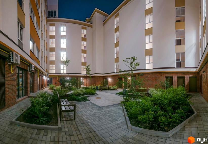 Зображення внутрішнього двору Клубного будинку Fort House. На фото будівля з великою кількістю вікон та озеленена прибудинкова територія.