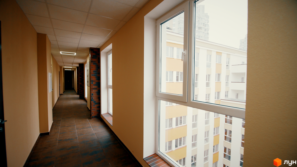 Клубний будинок Fort House: світлий коридор з великими вікнами та видом на сусідні будівлі. Опис новобудови для SEO.