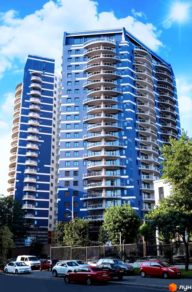 Житловий комплекс Alter Ego з синім фасадом та балконами. Навколо комплексу дерева та припарковані автомобілі.