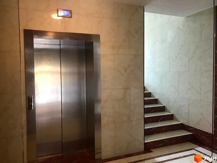 Ліфт у новому будинку ЖК Центральний. Мармурова плитка на стінах та сходах, що веде на верхні поверхи.