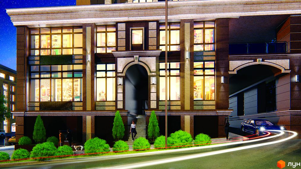 Житловий комплекс Володимирський. Фасад будівлі з великими вікнами та аркою входу. Перед будинком розташовані зелені насадження та дорога.