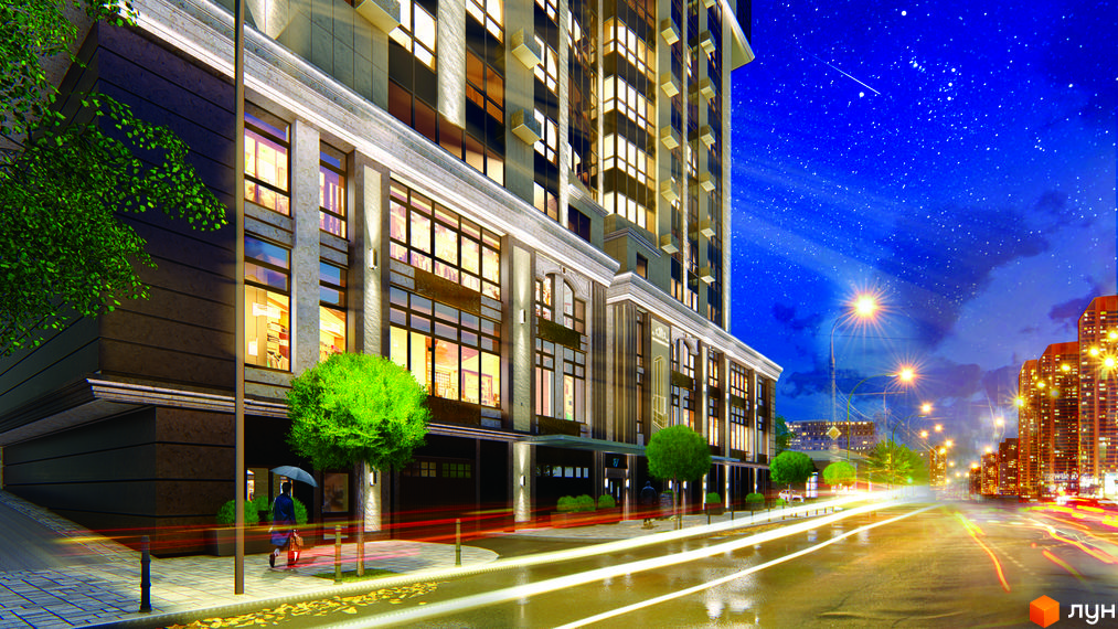 Зображення фасаду будинку ЖК Володимирський з великими вікнами та нічним освітленням. На передньому плані видно дорогу з ліхтарями та зелені насадження.