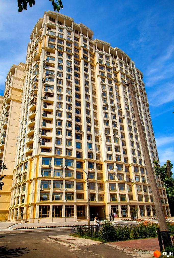 Житловий комплекс Golden Park: багатоповерховий будинок світло-жовтого кольору з великими вікнами. Перед будинком дорога та зелені насадження.