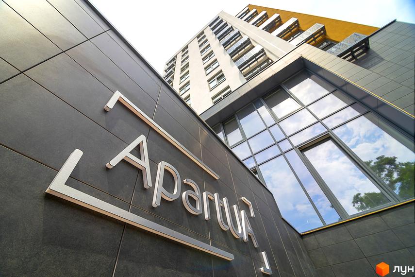 Зовнішній вигляд новобудови ЖК White Tower з сірою фасадною плиткою та великими вікнами, що відбивають небо. На фасаді видно об'ємні літери назви комплексу.