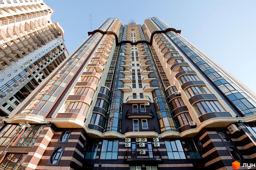 Висотна будівля житлового комплексу Престиж Холл з вигнутими формами, скляними балконами та комбінованим фасадом з темних і світлих панелей.