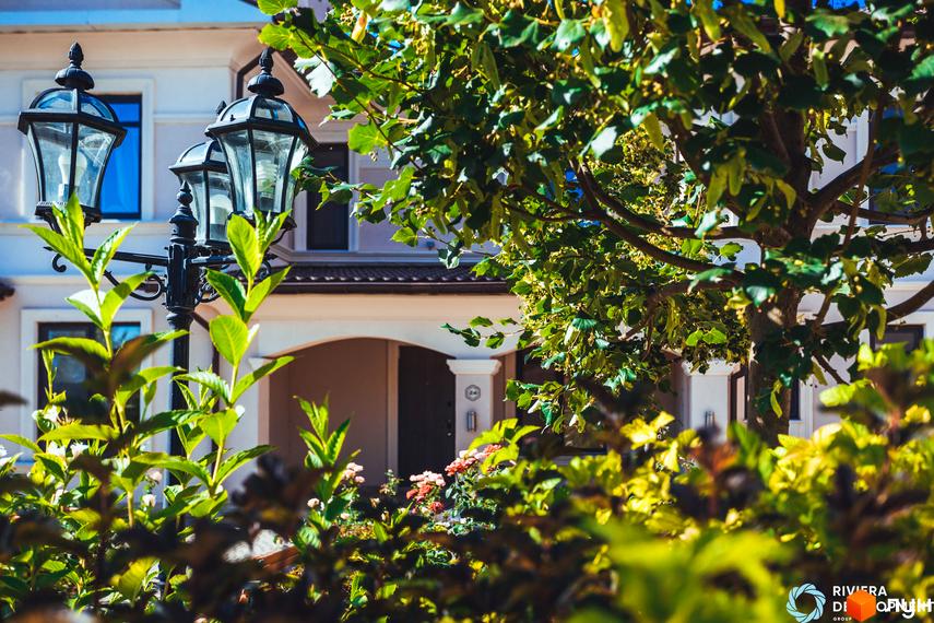 Зовнішній вигляд таунхаусів Villa Troyand. Будинки з двома поверхами, білі стіни, коричневий дах. На території зелені насадження та ліхтарі.