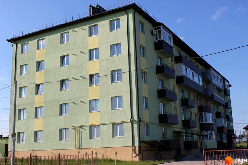 Зображення фасаду Житлового комплексу Ромашка. Багатоповерховий будинок з балконами та вікнами, прибудинкова територія з огорожею.