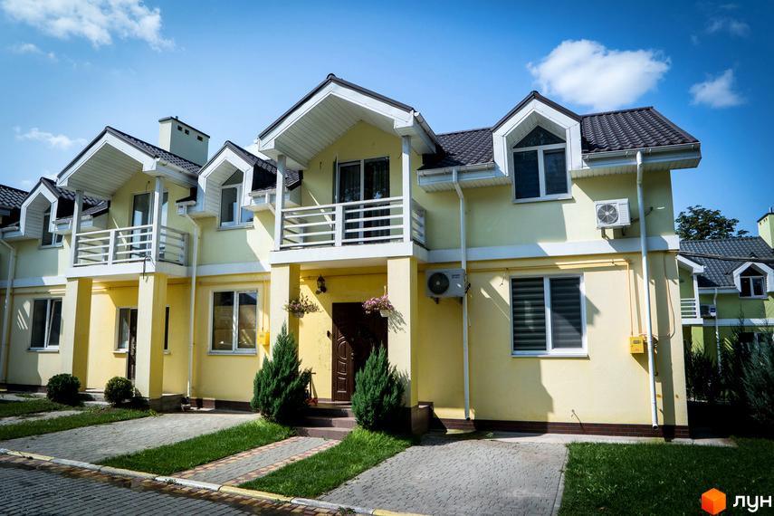 Зовнішній вигляд Котеджного містечка Sun City: двоповерхові будинки з балконами, сірим дахом та газоном біля дому. Вигляд з вулиці.