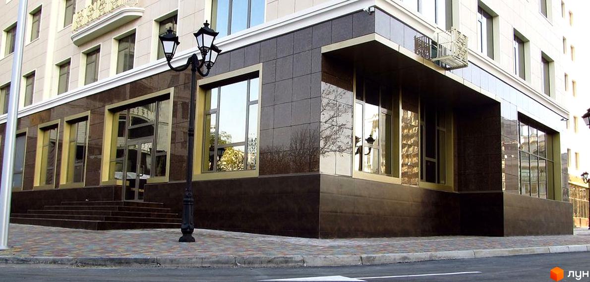 Житловий комплекс Перша Перлина з сучасним фасадом та вхідними сходами. Прибудинкова територія викладена плиткою та освітлена ліхтарями.