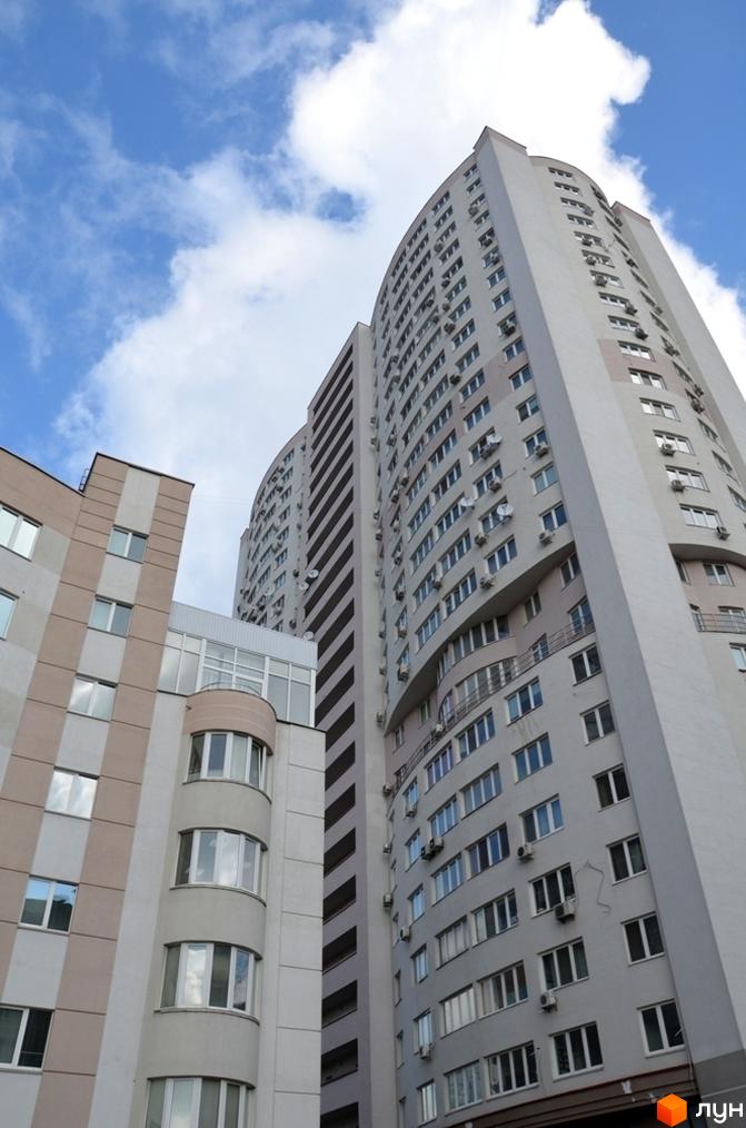 Житловий комплекс Вікторія: високі житлові будинки світлих відтінків з численними вікнами та кондиціонерами на фасадах під блакитним небом.