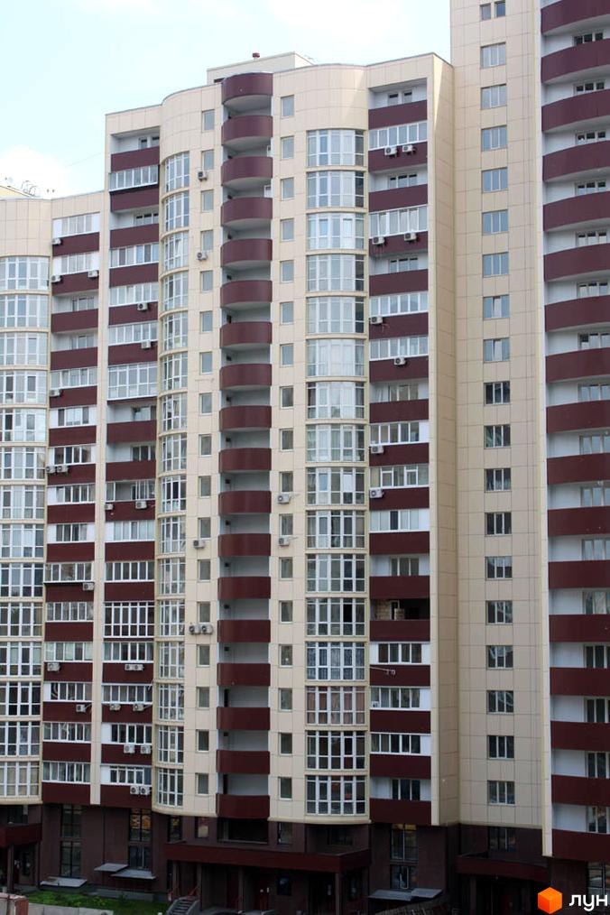 Багатоповерховий будинок Житлового комплексу Парковий з бежевими фасадами, коричневими балконами та великими вікнами. На передньому плані видно вхідну групу.